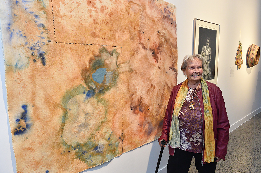 Artist Joyce Watson alongside one of her works on exhibition in Land, Sea and Sky.
